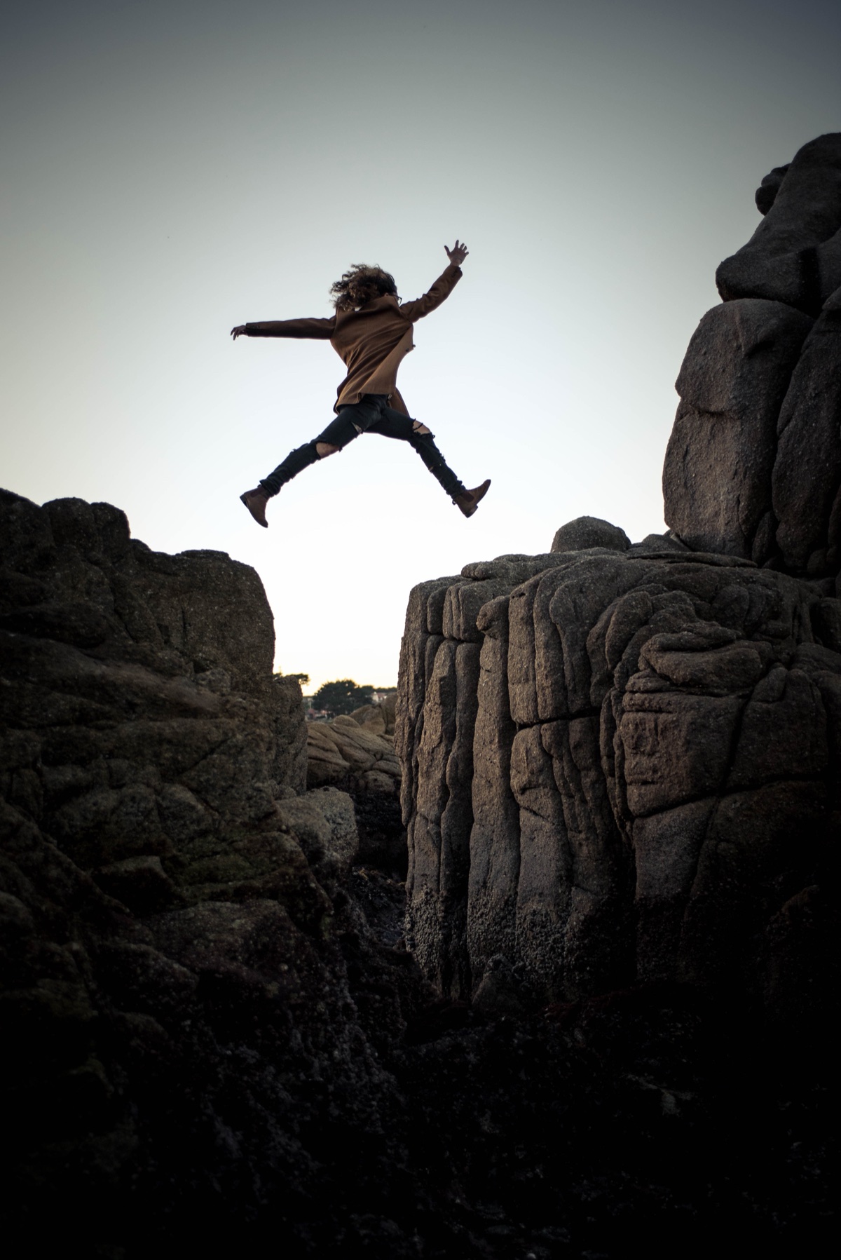 A woman leaping between two rock formations at dusk